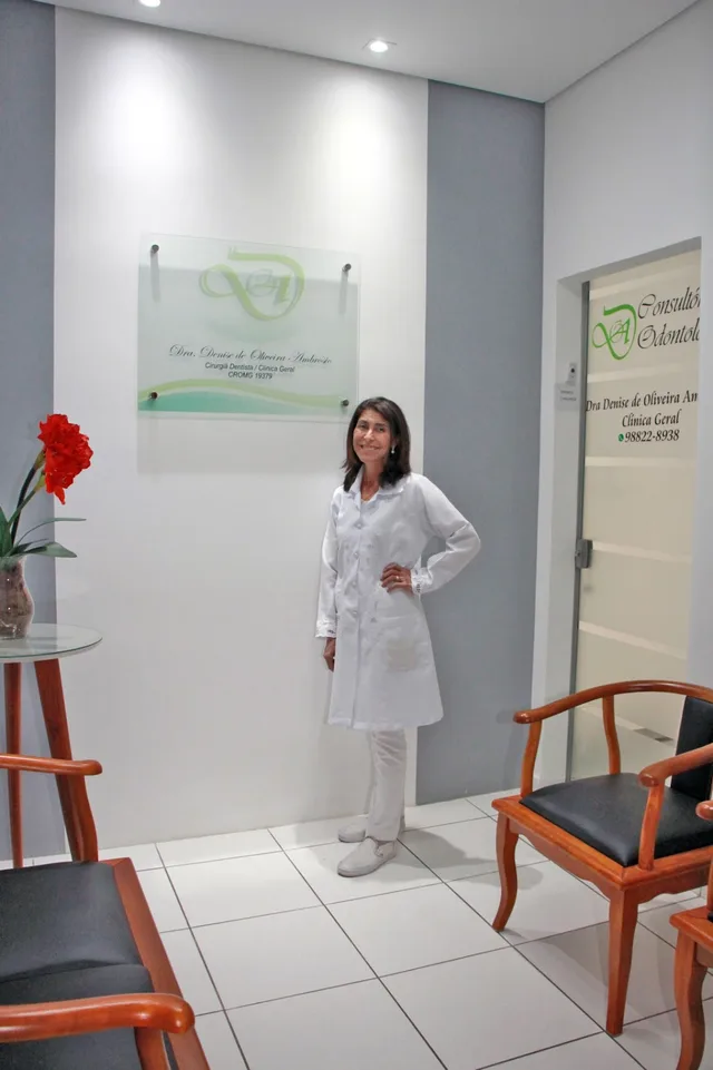Recepção com placa de vidro do monograma, cadeiras de madeira e porta de vidro do consultório